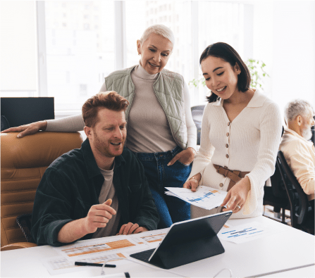 Group of casual business people surrounding a tablet and smiling