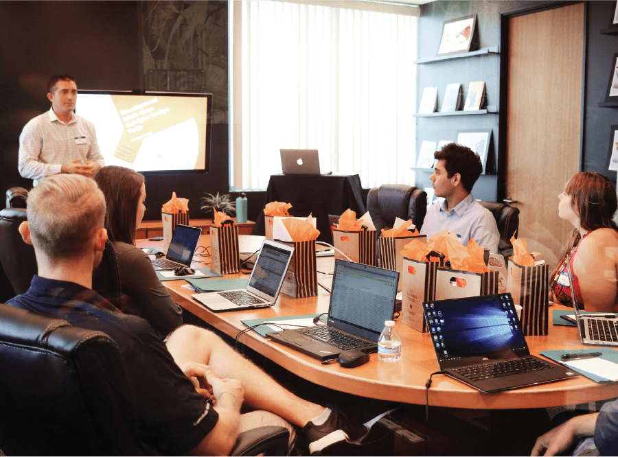 business conference with employees on laptops and presenter standing